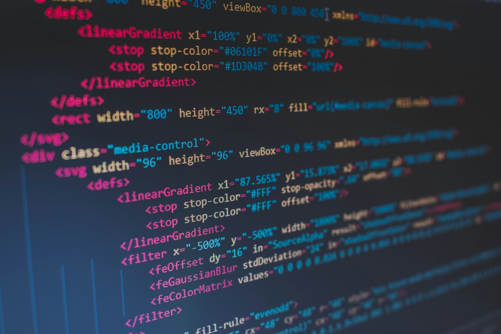 Close-up of HTML and SVG markup with pink tags and blue attribute values on a dark code editor screen
