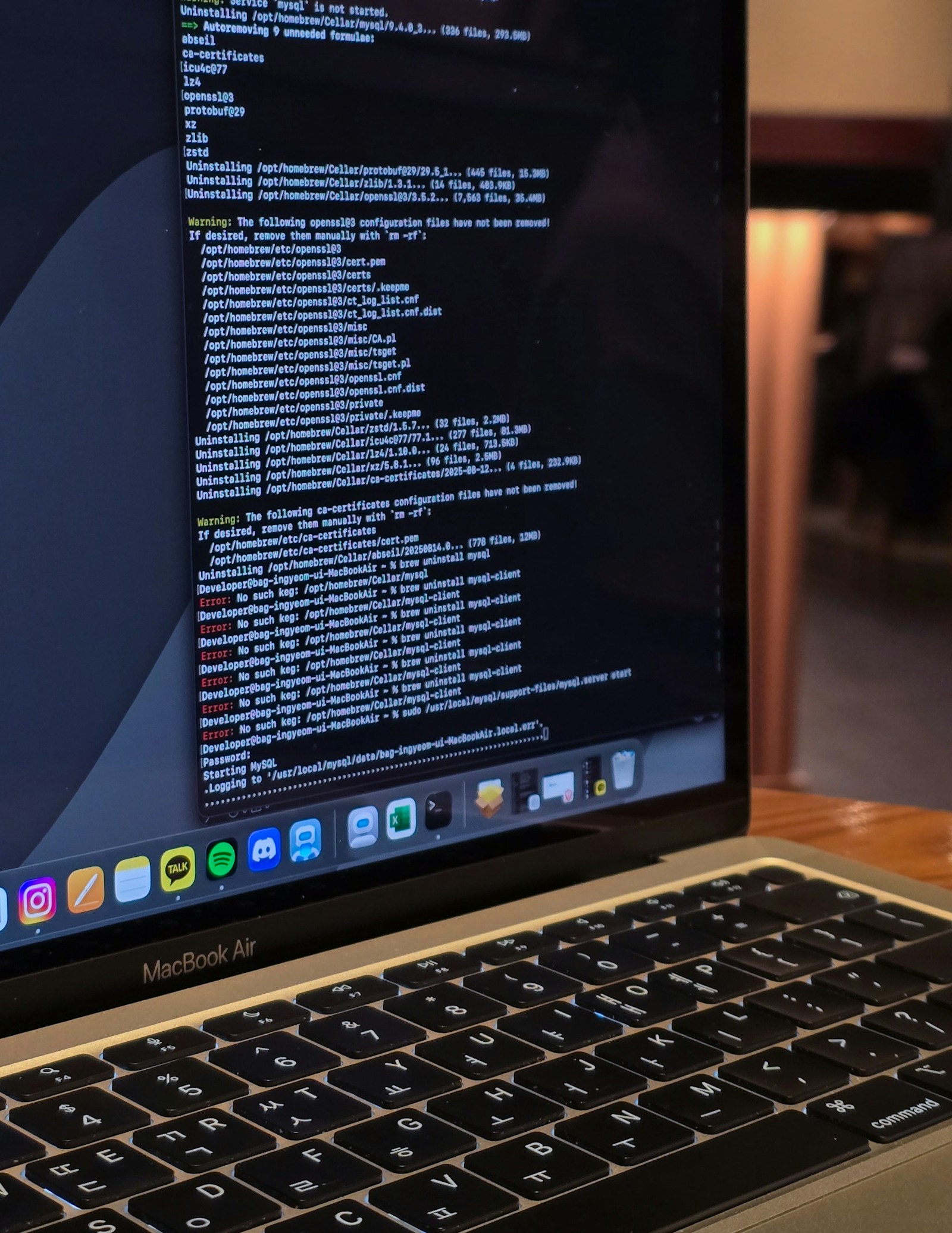 A MacBook Air terminal shows Homebrew uninstall output and repeated errors while a developer tries to start MySQL