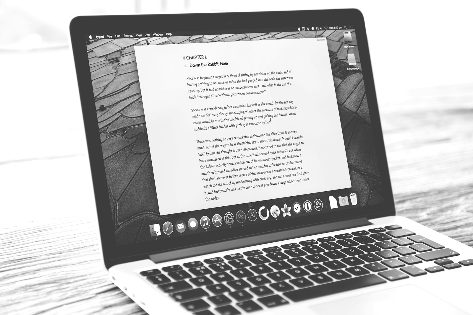 An open laptop on a wooden table shows a long page of dense text in black and white