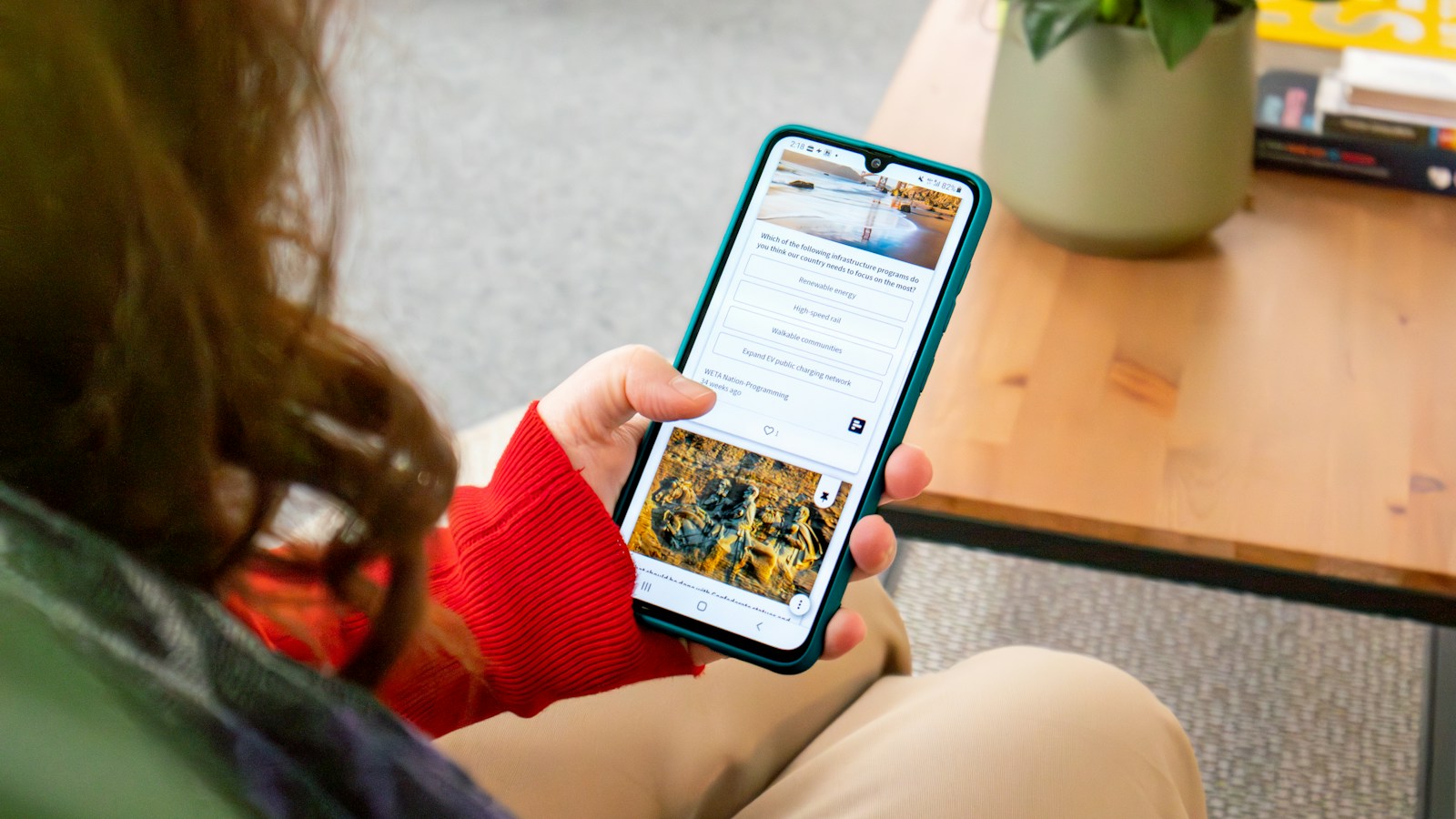 Over-the-shoulder view of a person in a red sweater reading a page of text and options on a phone
