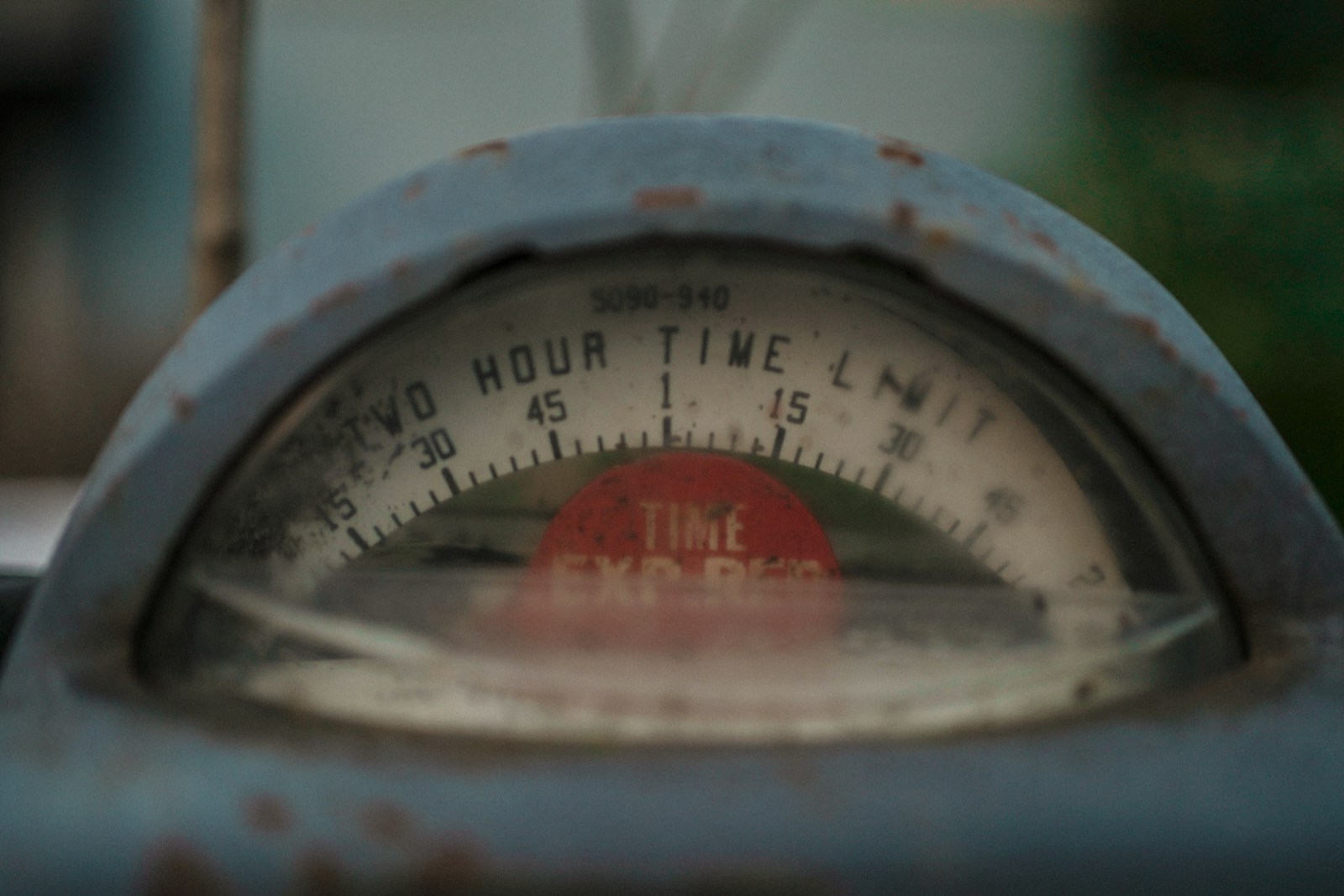 Close-up of a weathered parking meter dial marked two hour time limit, with a red time expired flag showing