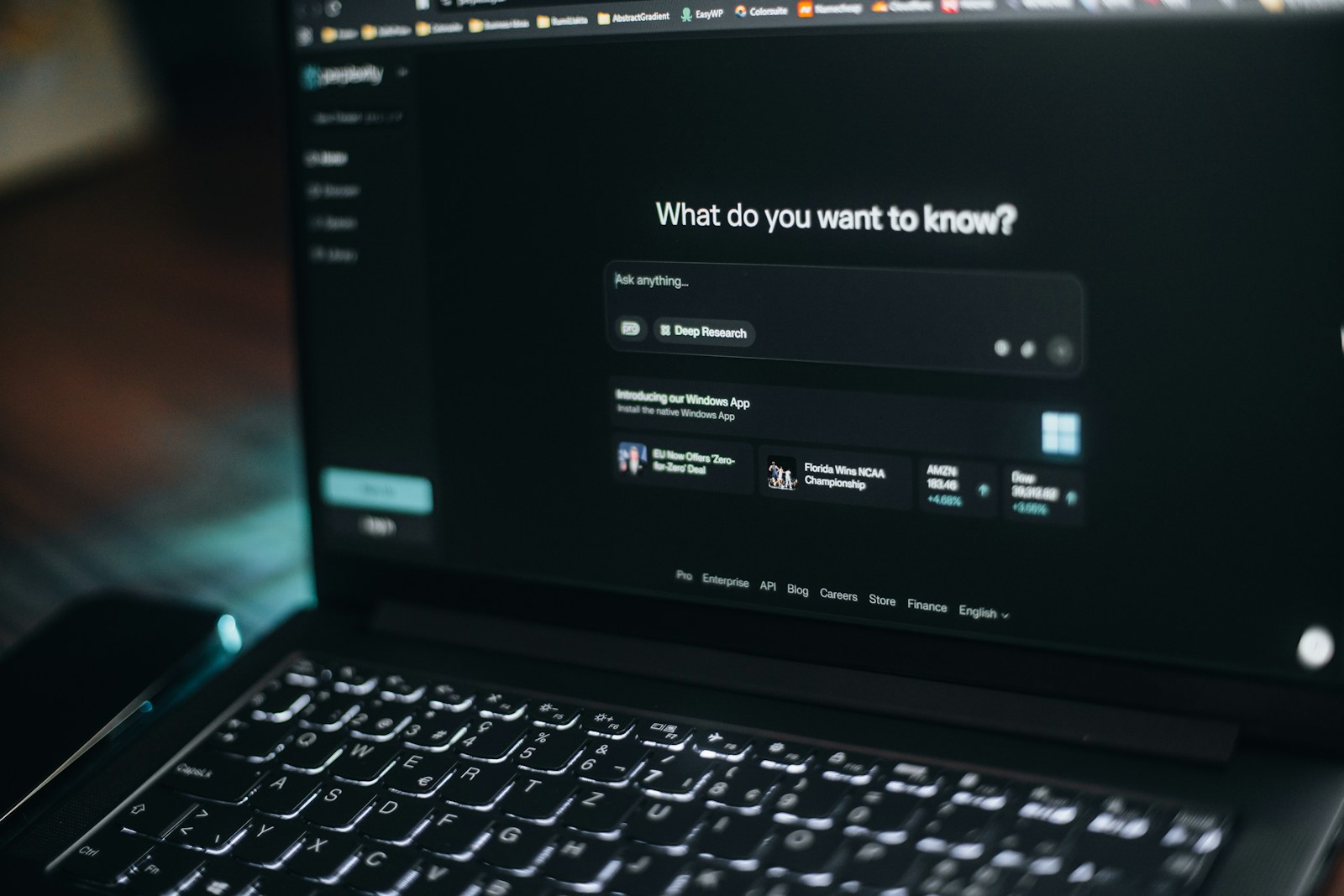 A dark laptop shows Perplexity's home screen asking What do you want to know above an Ask anything box