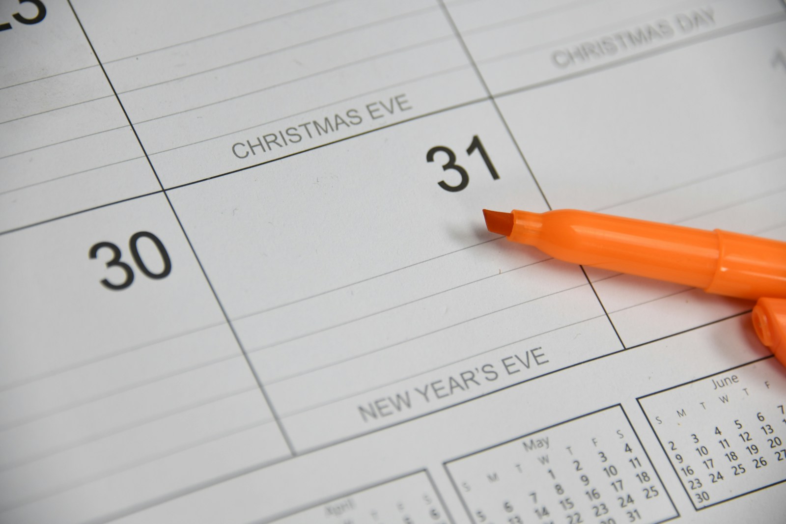 An orange highlighter lies on a printed December calendar next to the 31st, which is labelled New Year's Eve