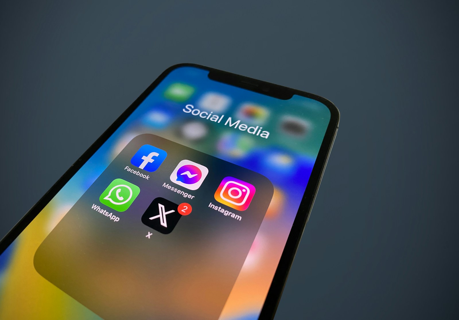 Close-up of a smartphone showing a Social Media folder with Facebook, Messenger, WhatsApp, Instagram and X app icons